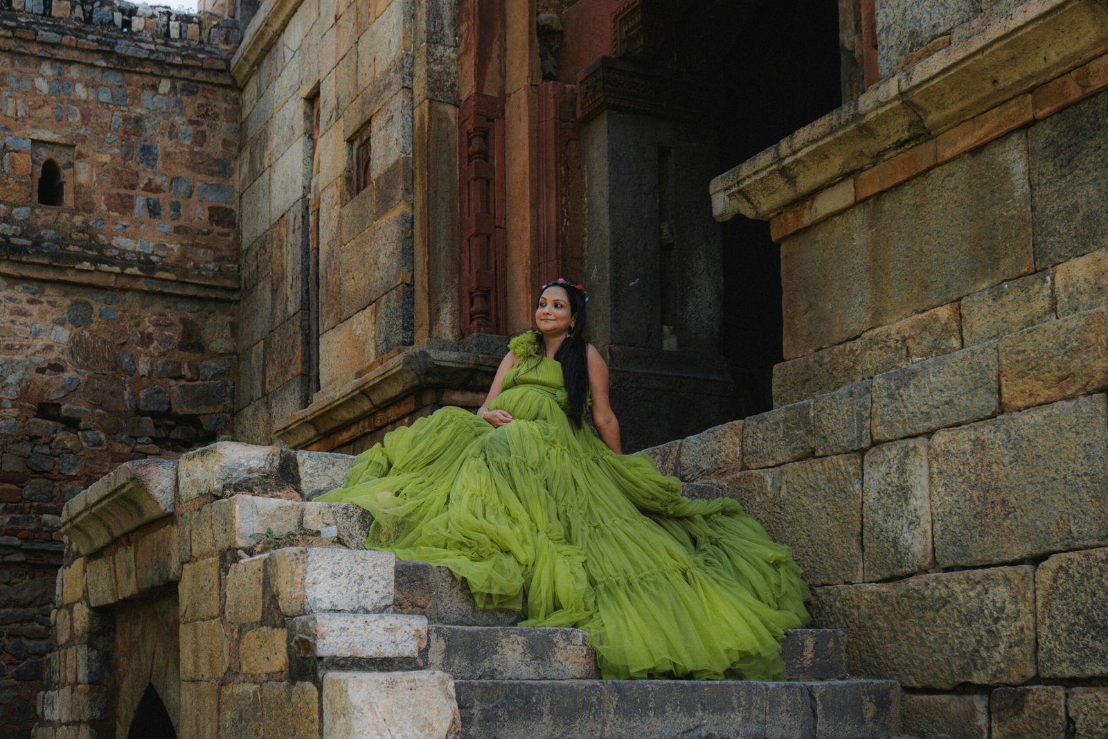 Woman in a flowing green dress on stone steps.
