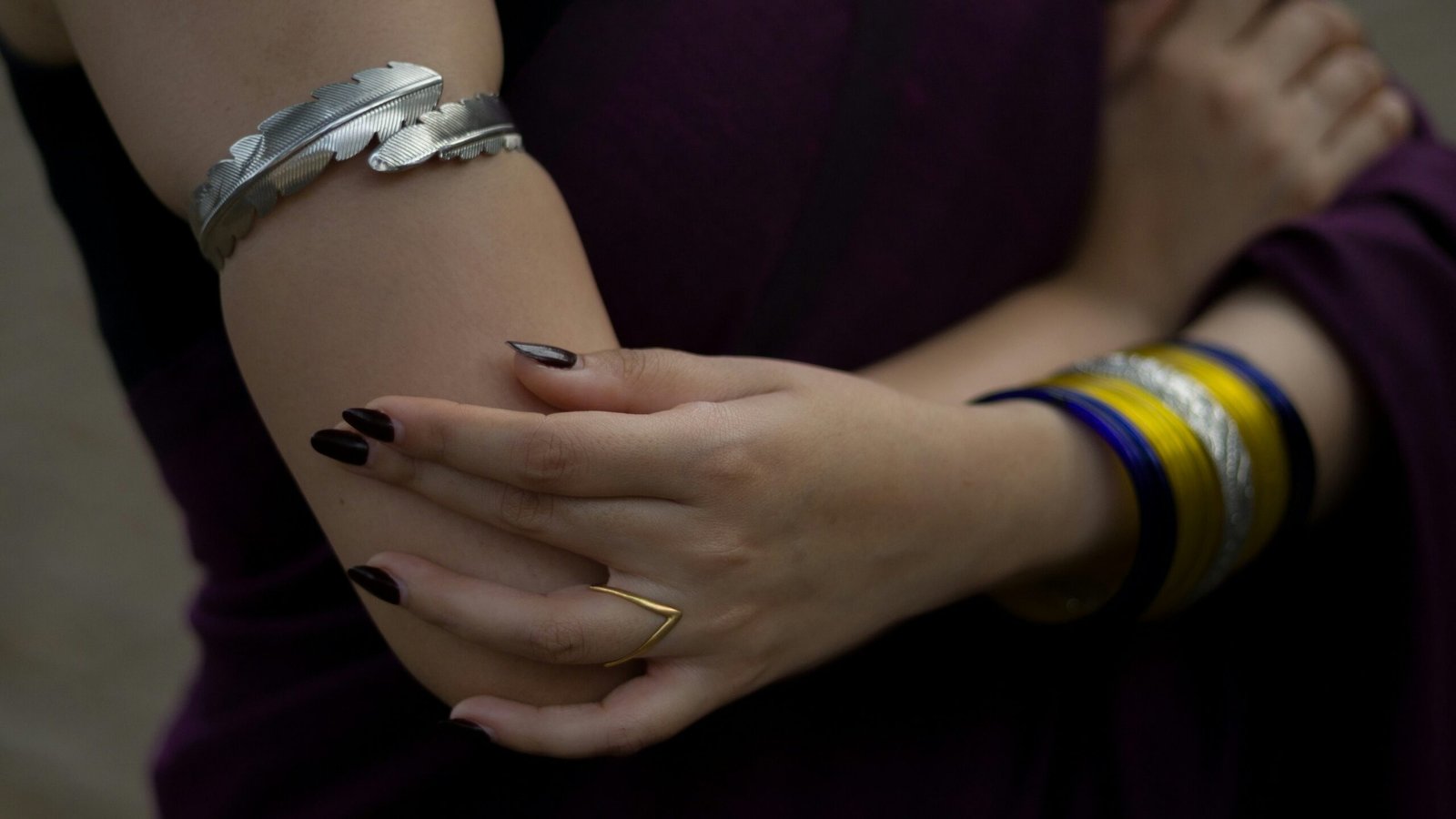Woman's arms are crossed, adorned with jewelry.
