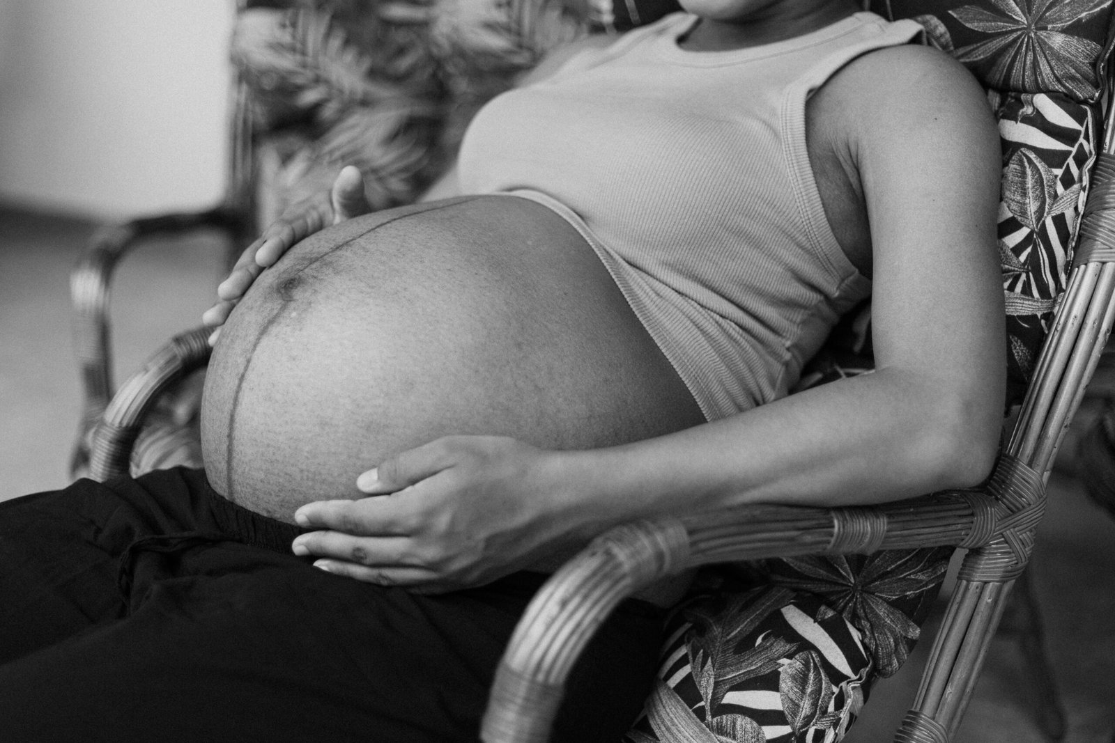 a black and white photo of a pregnant woman sitting in a chair
