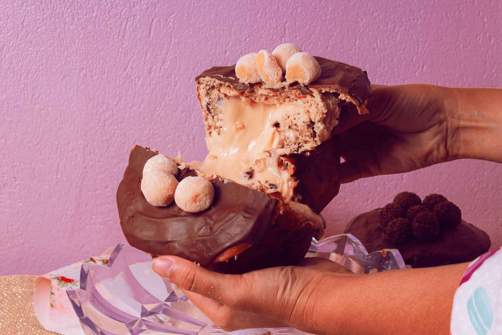 a person holding a piece of chocolate covered doughnut