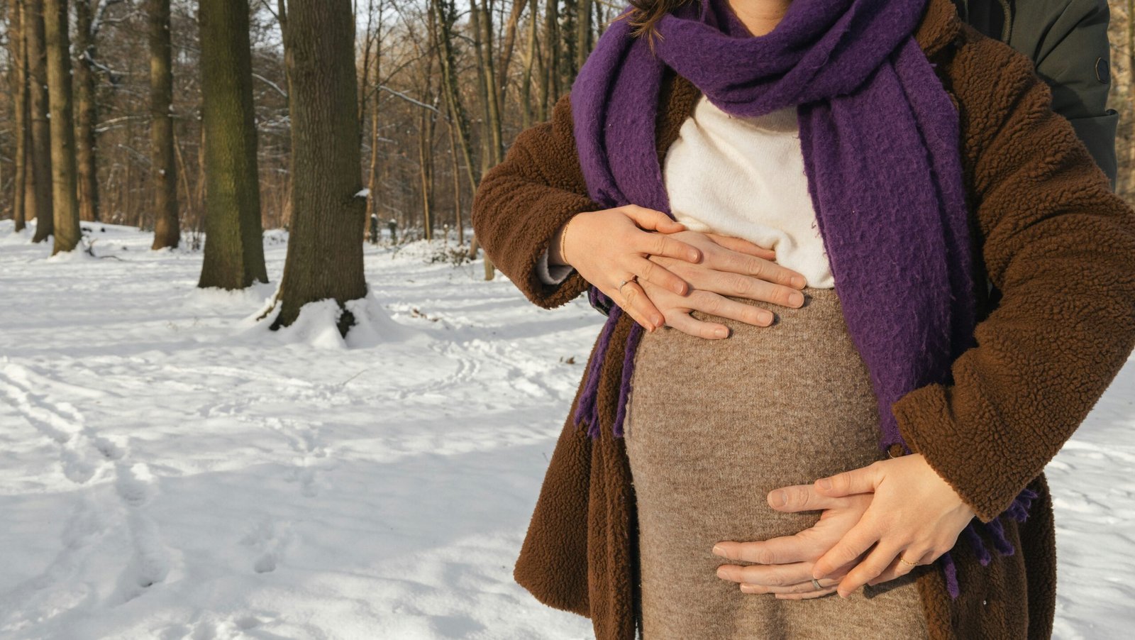 a woman standing in the snow holding her stomach