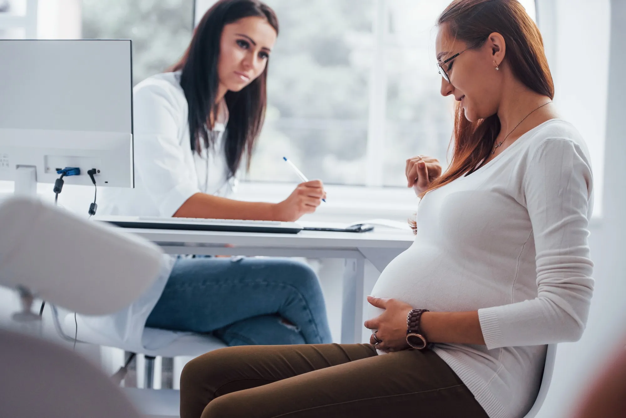 Active conversation. Pregnant woman have consultation with obstetrician indoors.