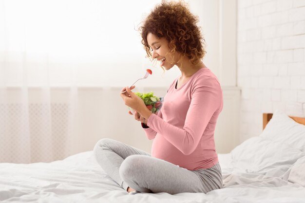 Africanamerican expectant girl enjoying healthy vegetable salad