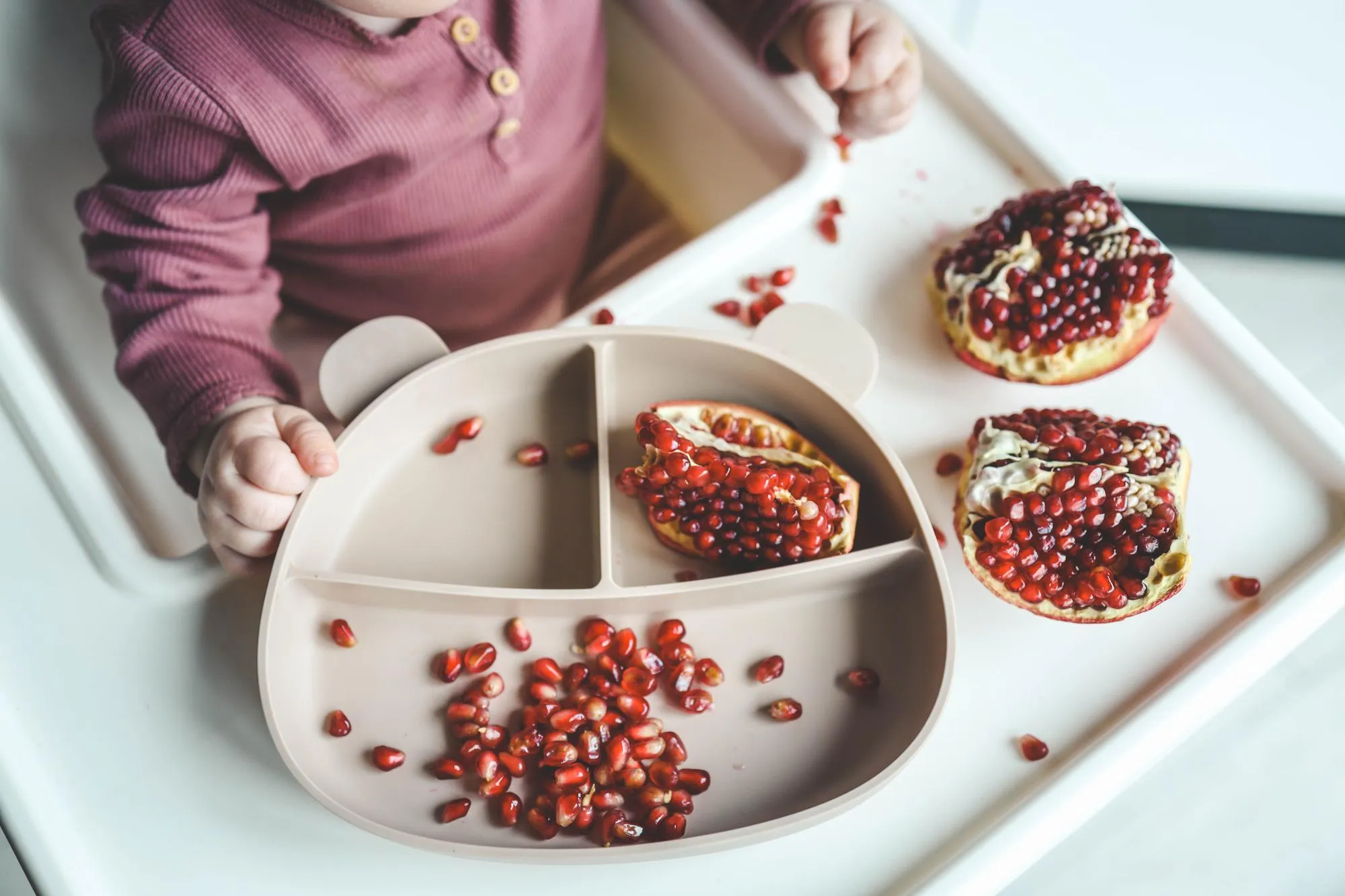 Baby eats pomegranate first complementary feeding concept