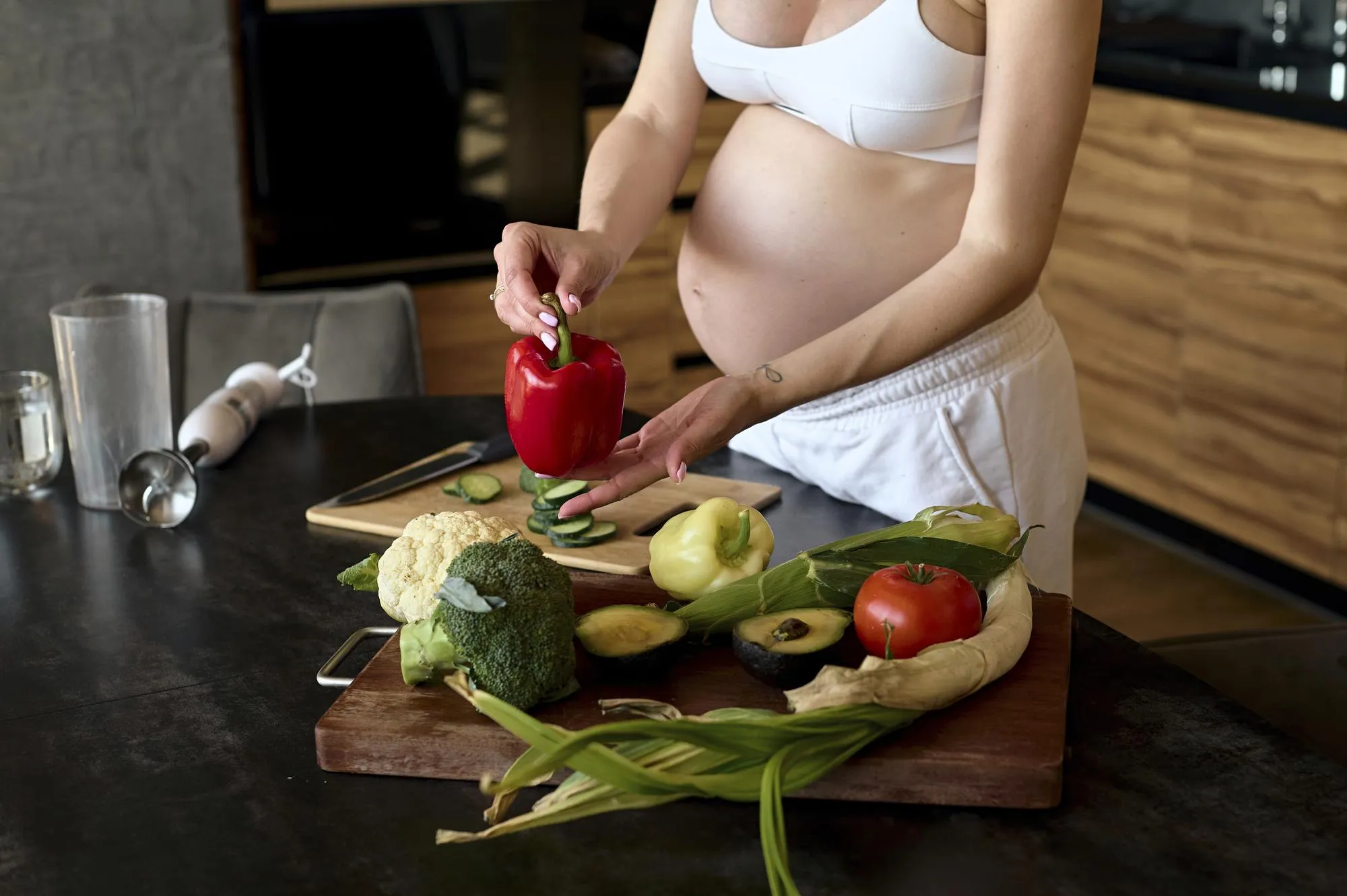 Beautiful pregnant woman making fruits smoothies with blender H