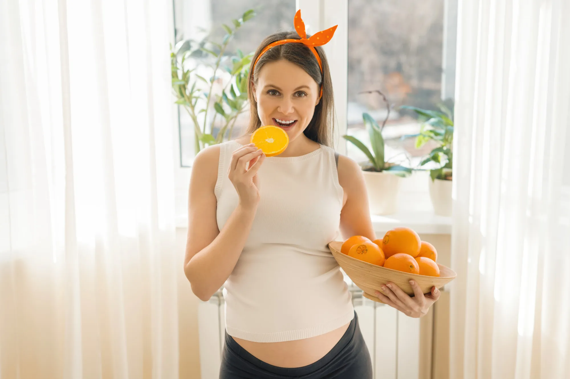 Beautiful smiling pregnant woman with oranges