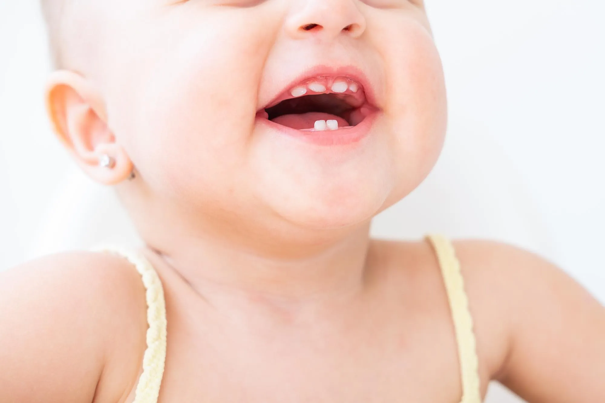 close up baby girl smiling with first milk teeth