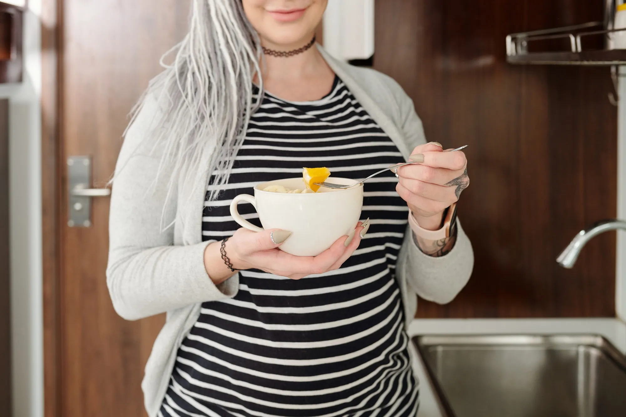 Cropped portrait of smiling young pregnant woman having bowl of fruit salad for snack