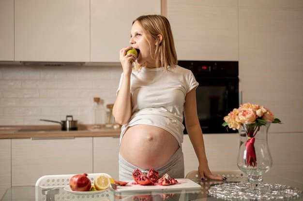 Front view pregnant woman eating an apple