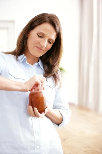 Frustrated difficult and woman with tight jar for healthy food with nutrition struggle and container for storage Mature female person and annoyed with problem for glass jug peach jam and hungry