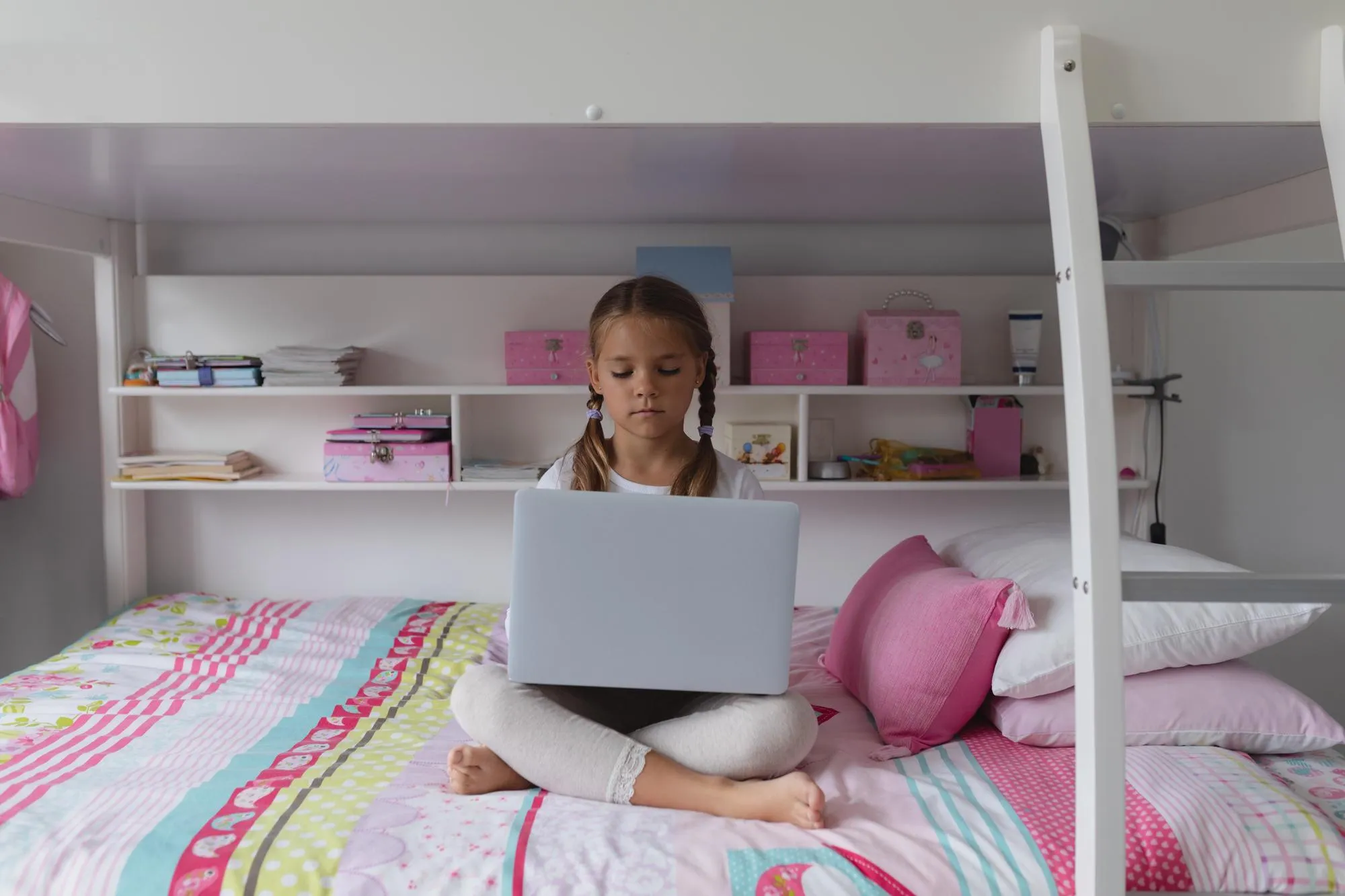 Girl using laptop on bed in a comfortable home