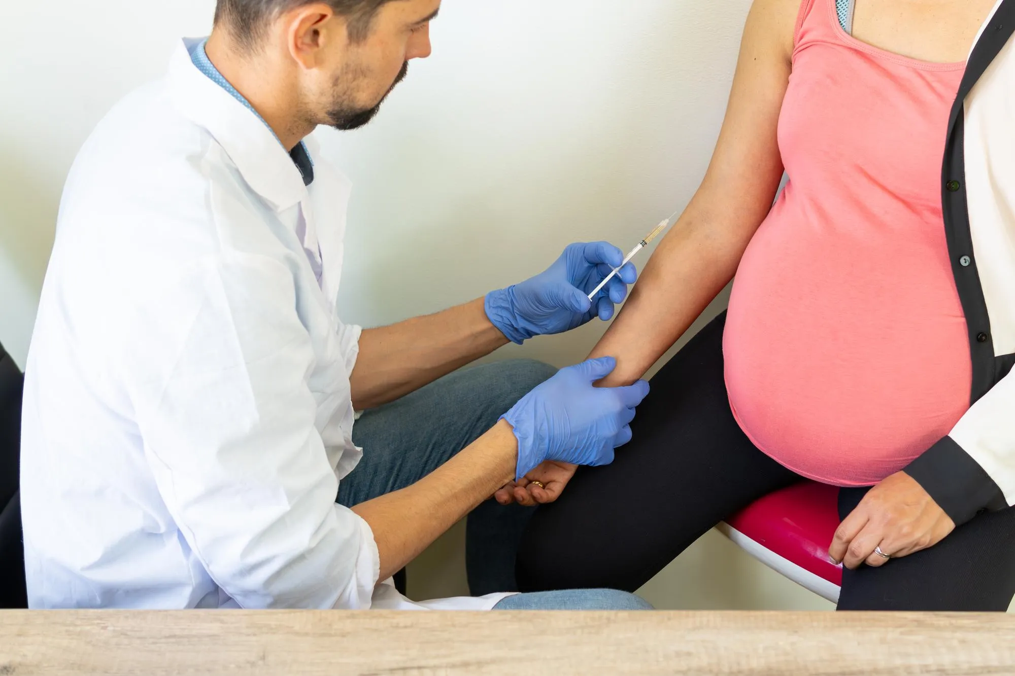 Health Care A Brown Caucasian Doctor Vaccinates A Young Pregnant Woman With Big Arm Tummy