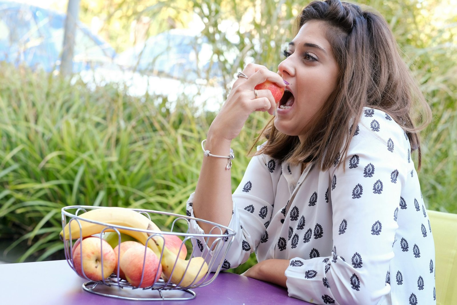 a woman sitting at a table eating an apple