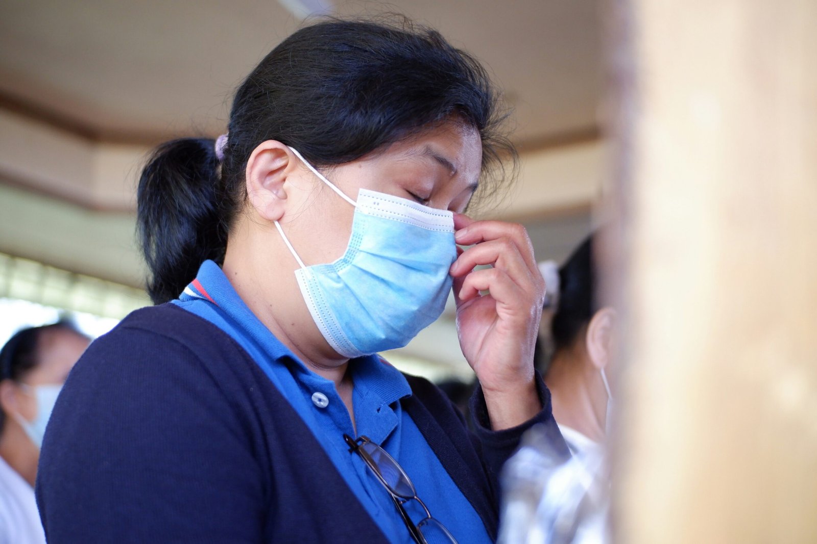 woman in blue shirt covering face with white paper