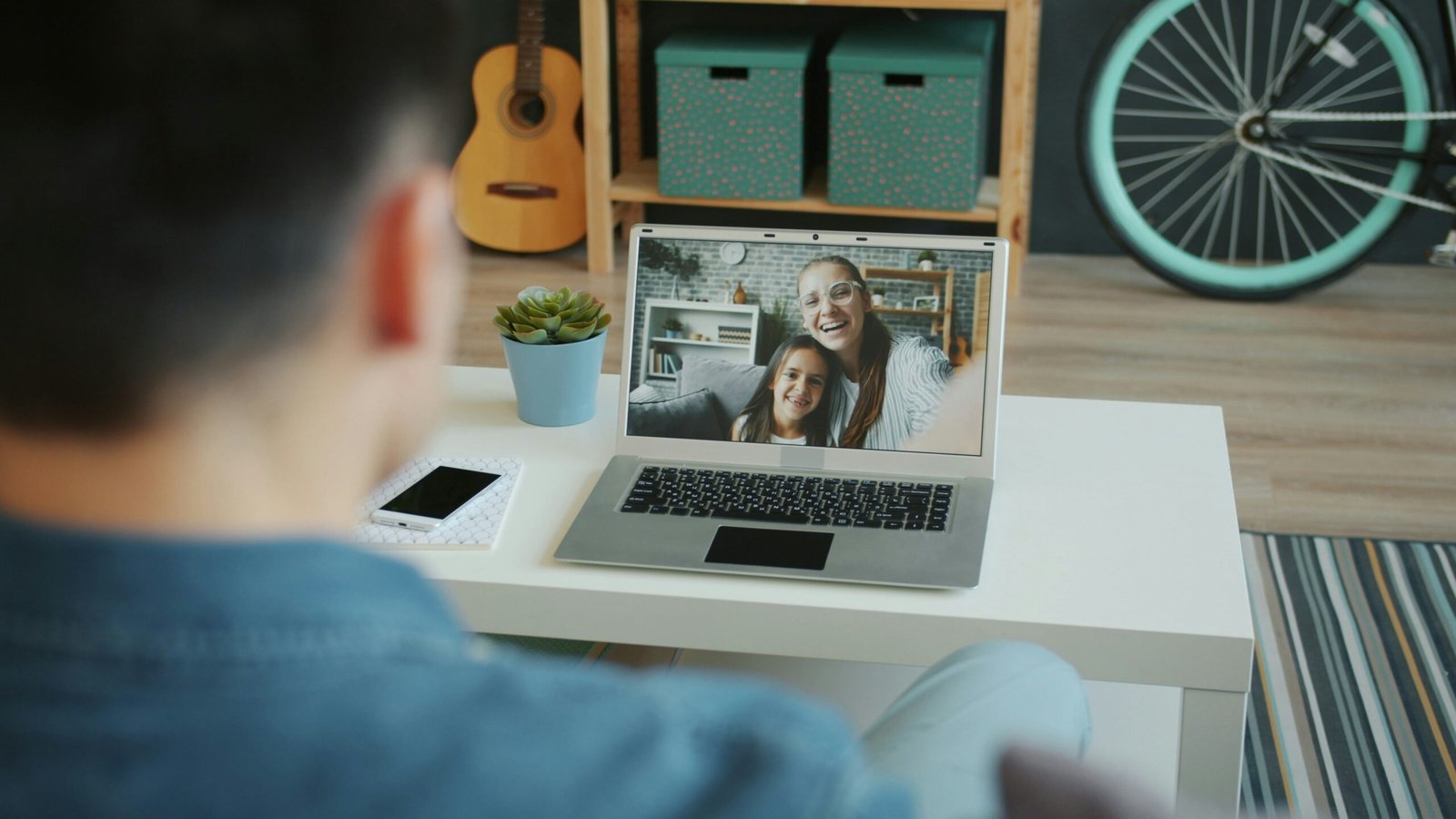 Man video calls two smiling women on laptop.