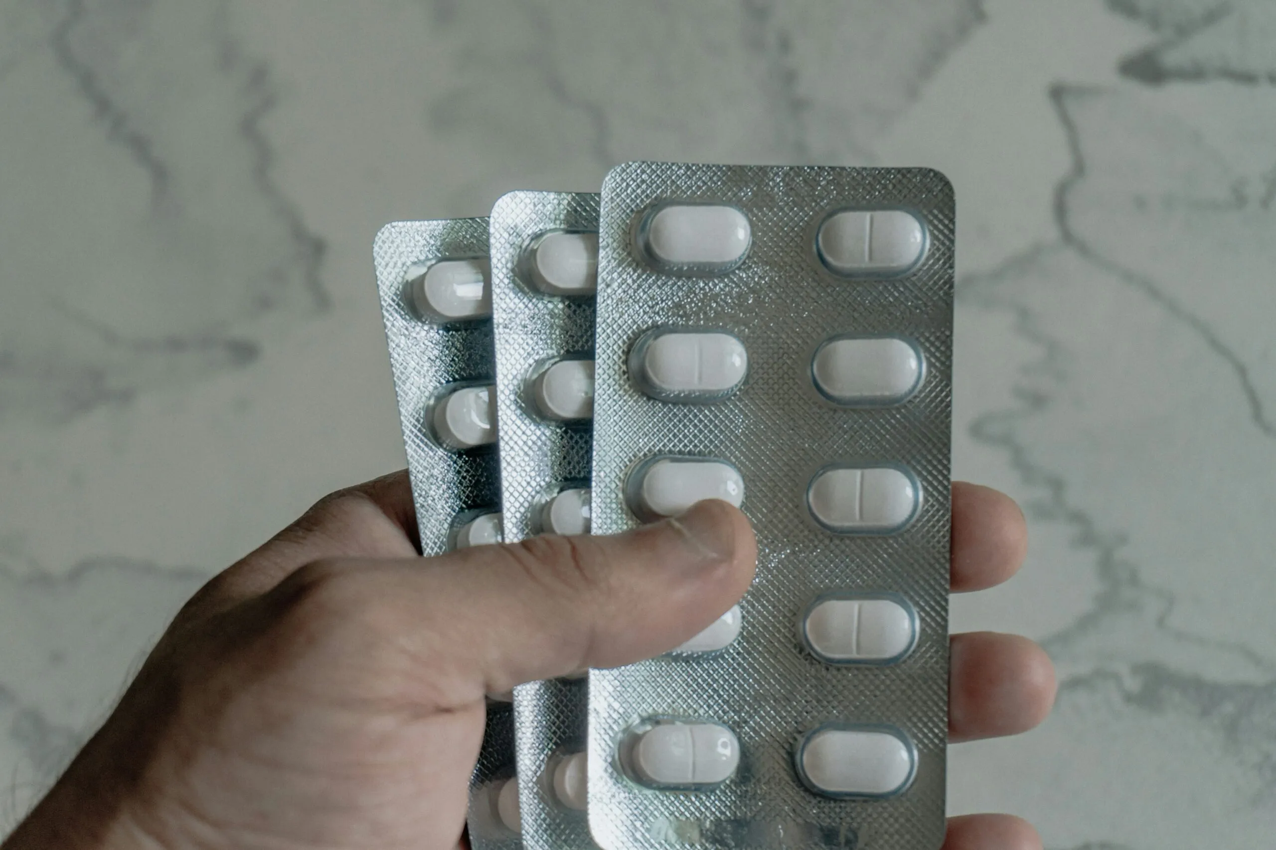 Hand holding blister packs of white pills