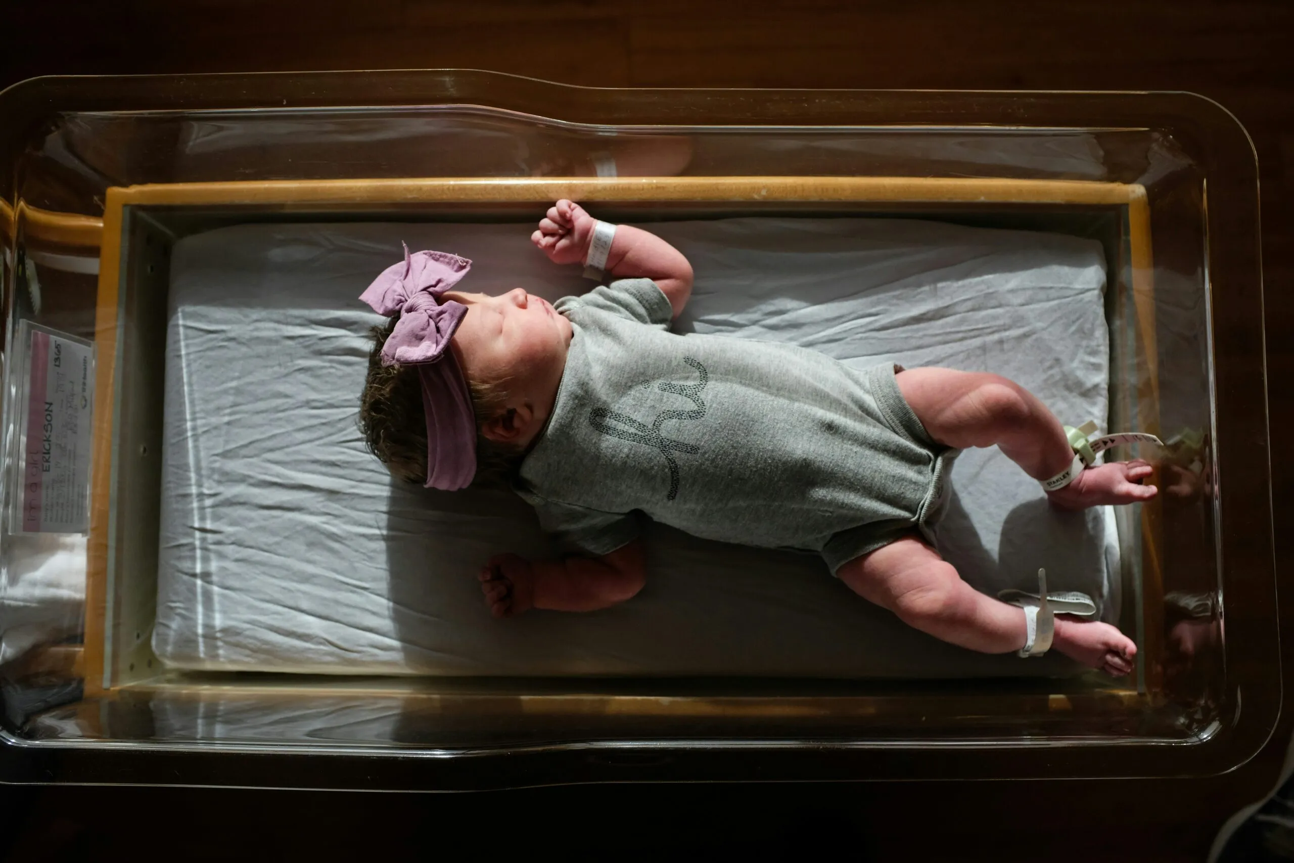 a baby laying on a bed with a pink headband