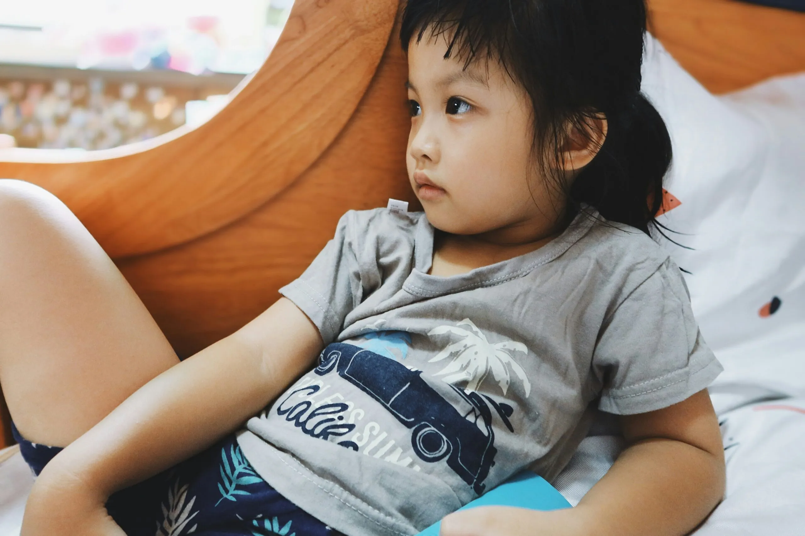 boy in gray crew neck t-shirt lying on bed