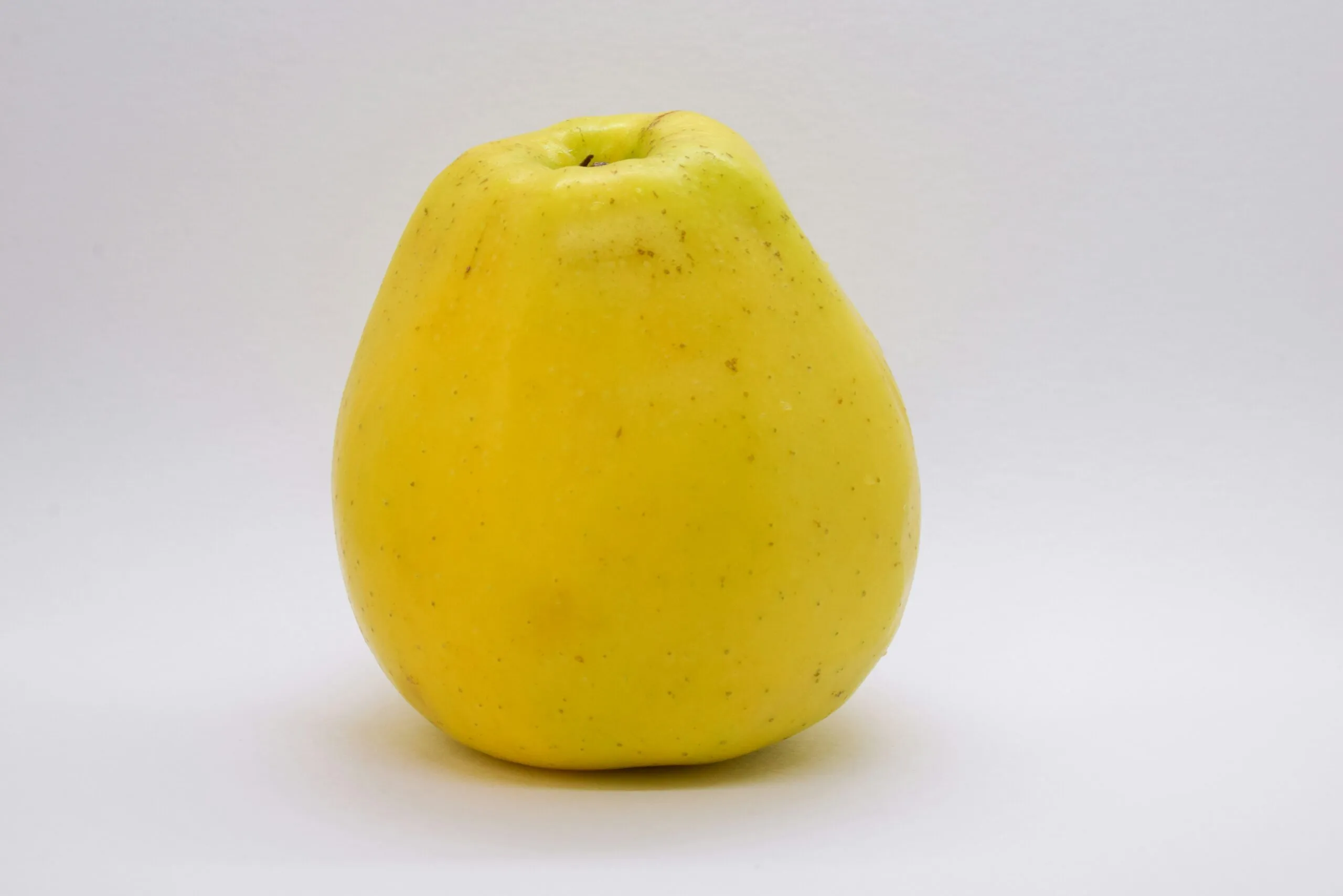 a yellow apple sitting on top of a white table