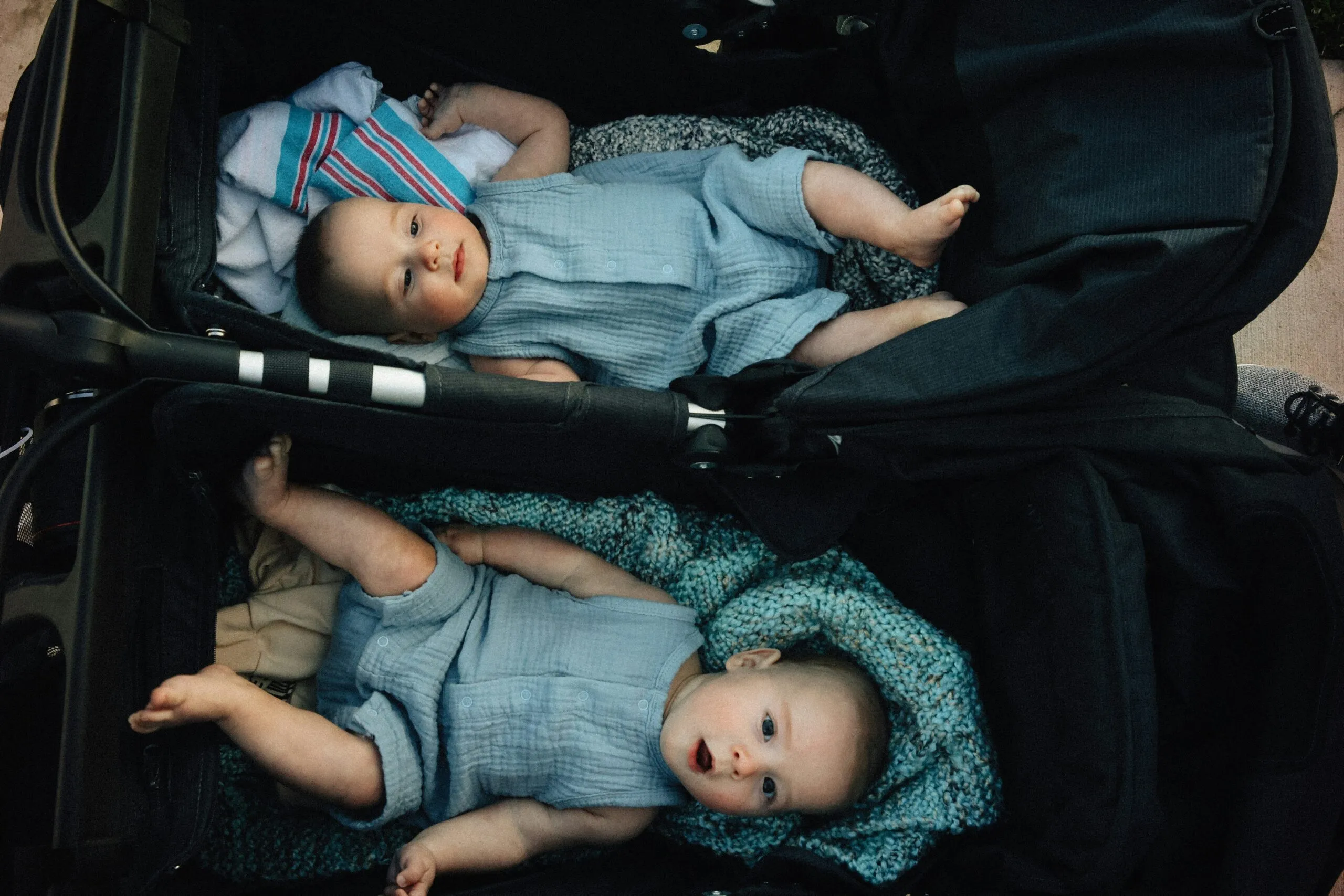 Two babies are resting in a stroller.