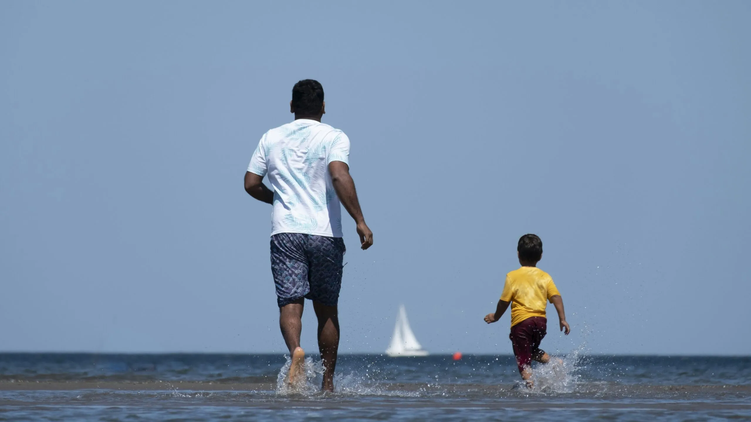 Father and son running into the calm ocean.