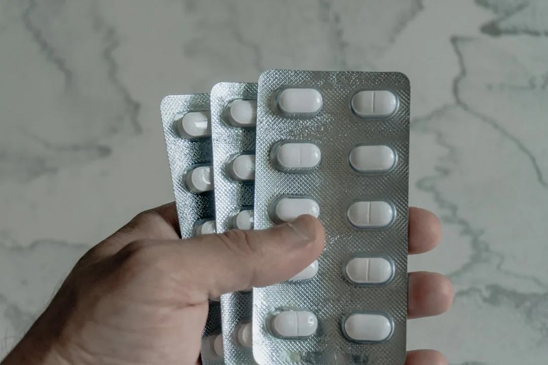 Hand holding blister packs of white pills