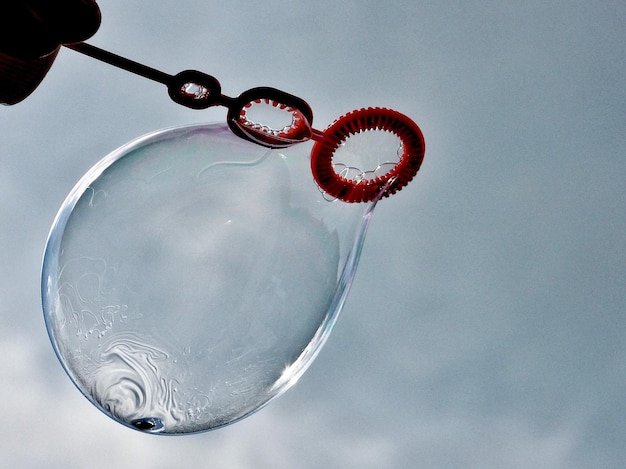 Low angle view of person holding ice cream against sky