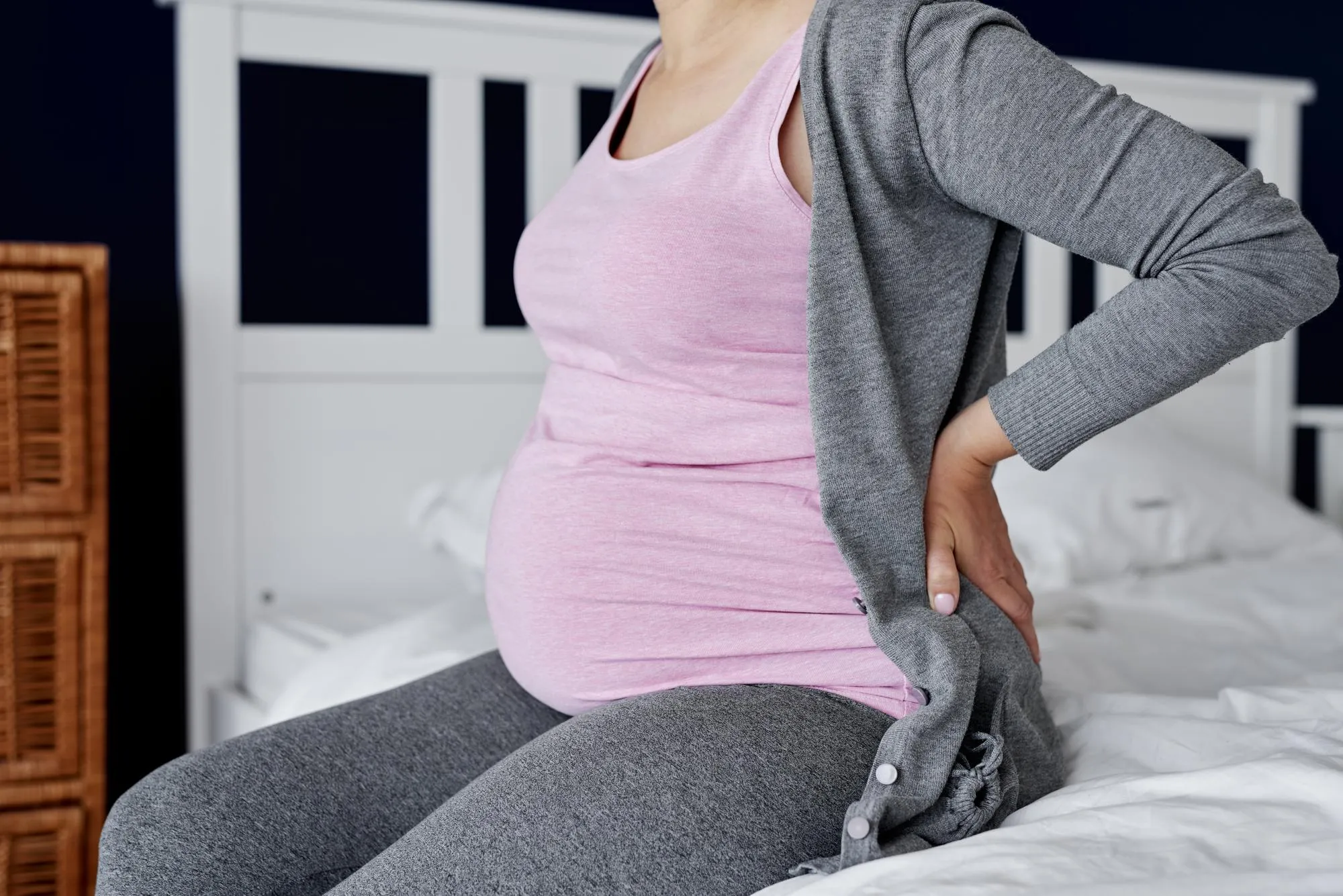 Midsection of woman sitting on bed at home