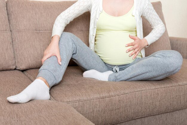 Midsection of woman sitting on sofa at home