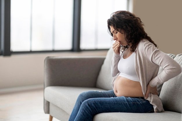 Morning Sickness Pregnant Woman Suffering Nausea While Sitting On Couch At Home
