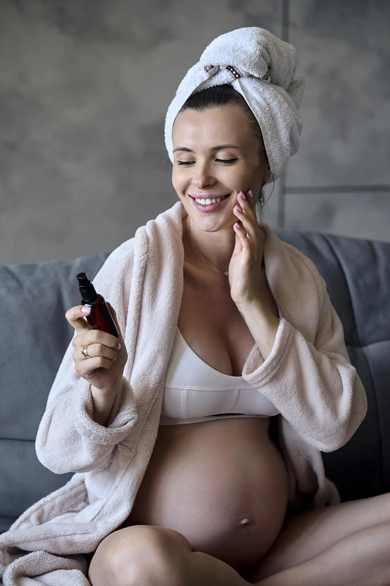 Portrait of a beautiful pregnant woman sitting on a sofa and doi