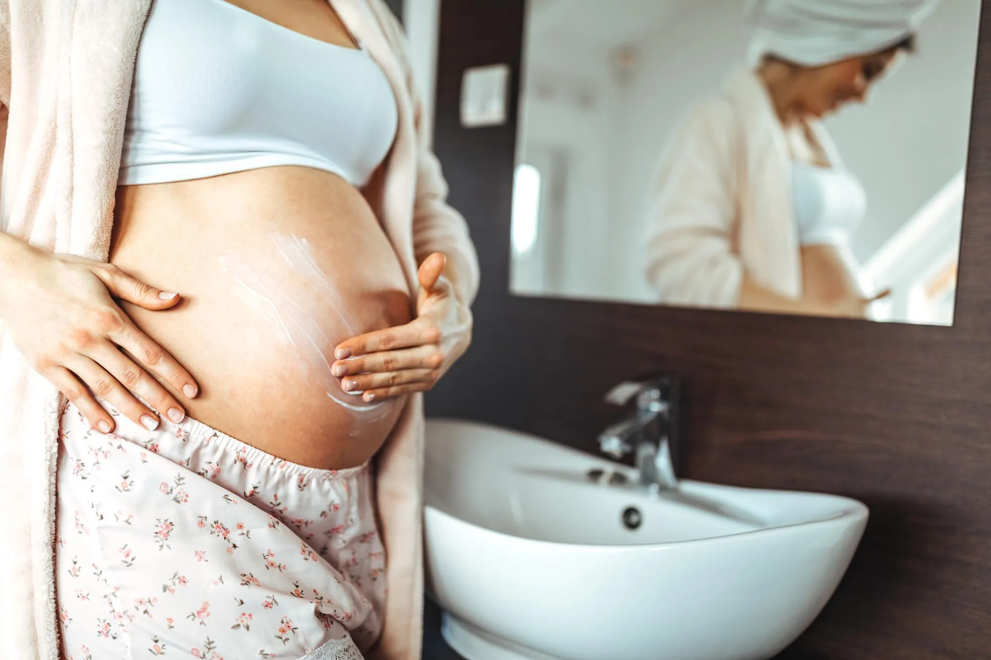 Pregnant woman applying creme on her belly