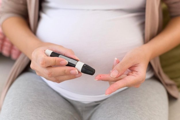 Pregnant woman checking blood sugar level by using Digital Glucose meter