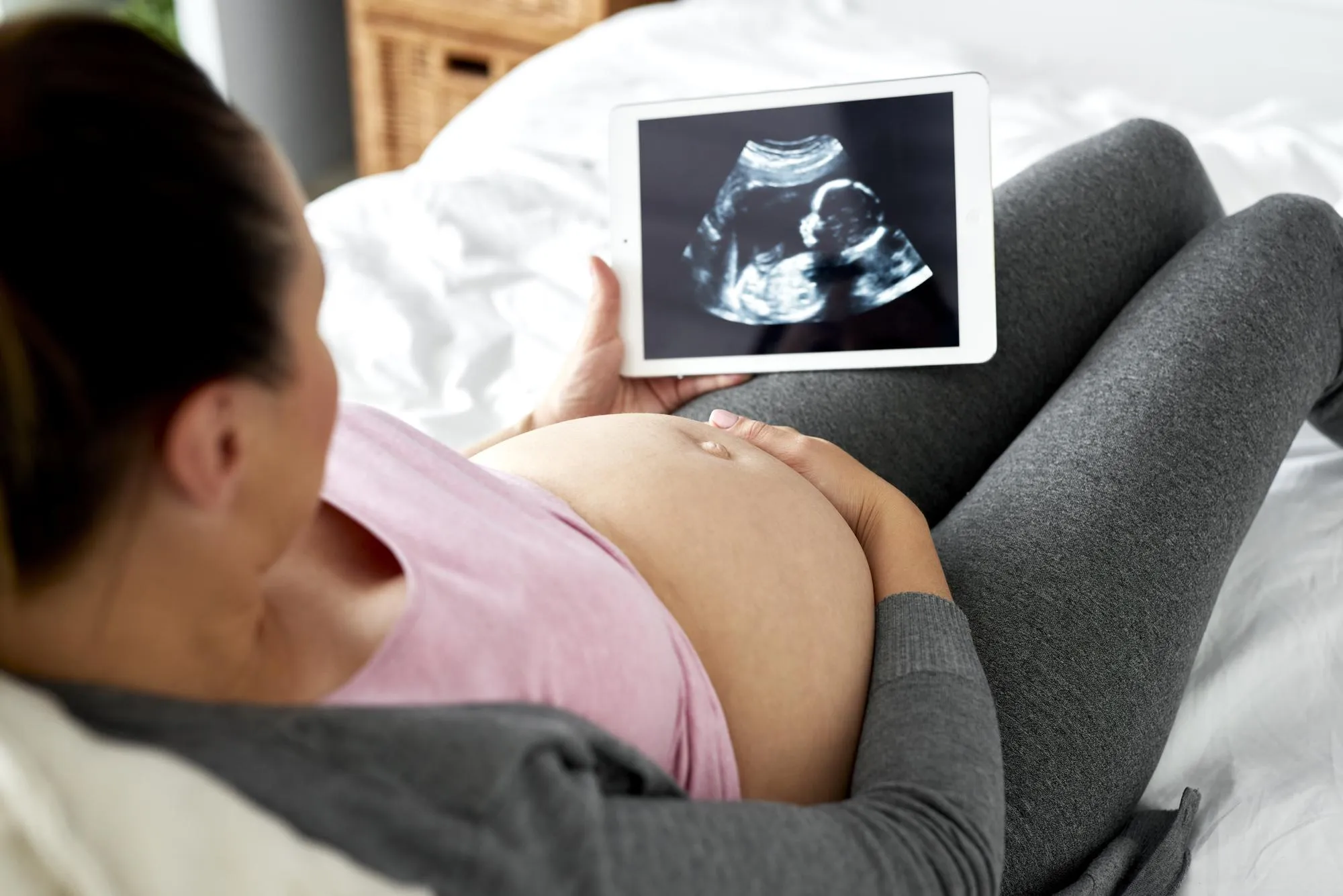 Pregnant woman watching at ultrasound record on tablet