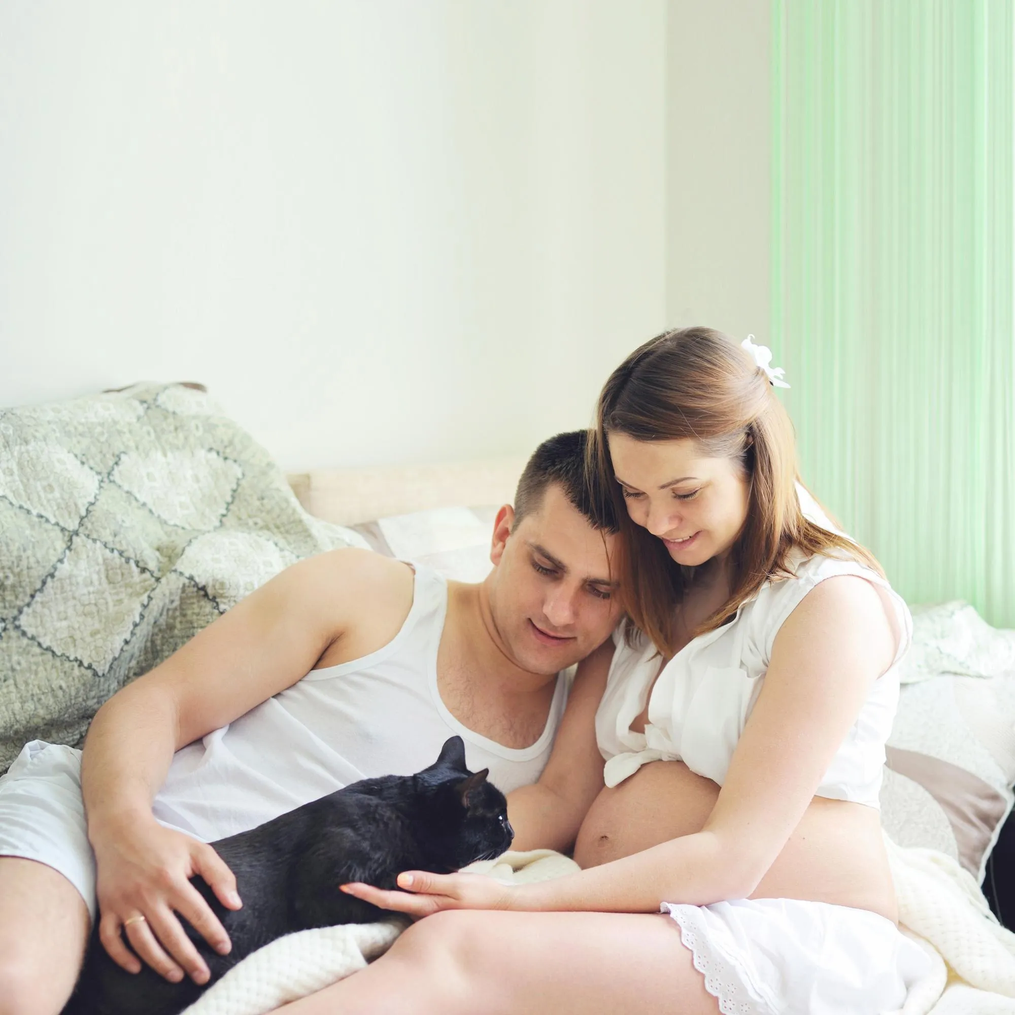 Pregnant woman with future dad have a leisure with cat