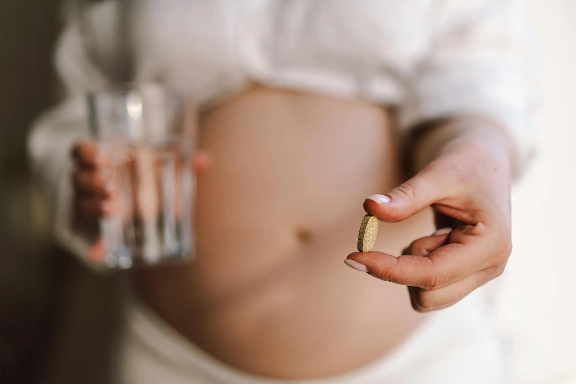 Pregnant young woman holding vitamins