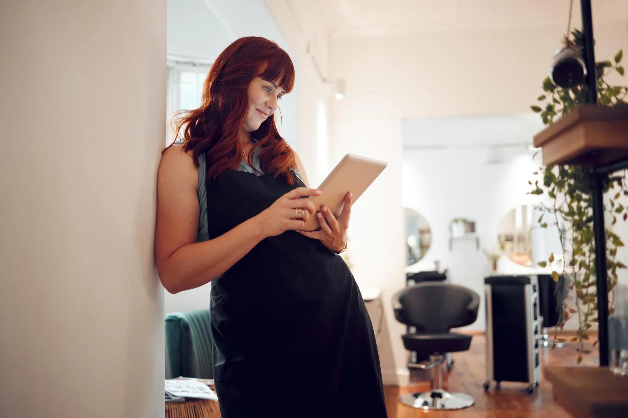 Salon tablet and schedule with a woman hairdresser checking her appointment or online booking Calendar technology and stylist with a female worker or small business owner in the hair care industry