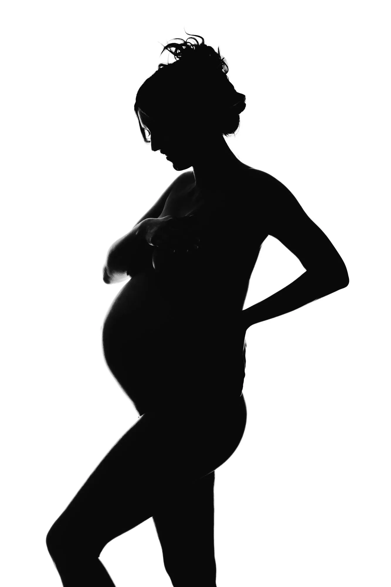Side view of silhouette woman covering breasts while hand on back against white background
