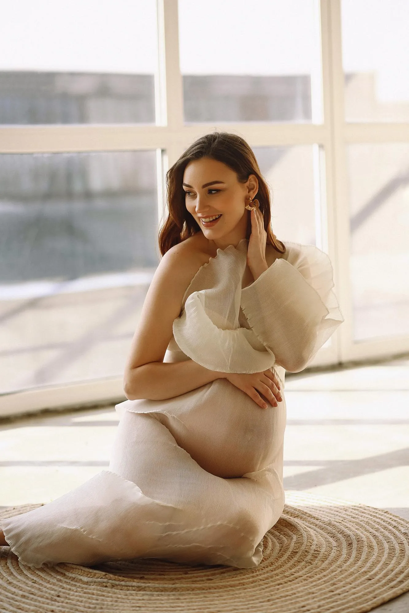 Vertical portrait of attractive pregnant woman in stylish transparent dress in the studio