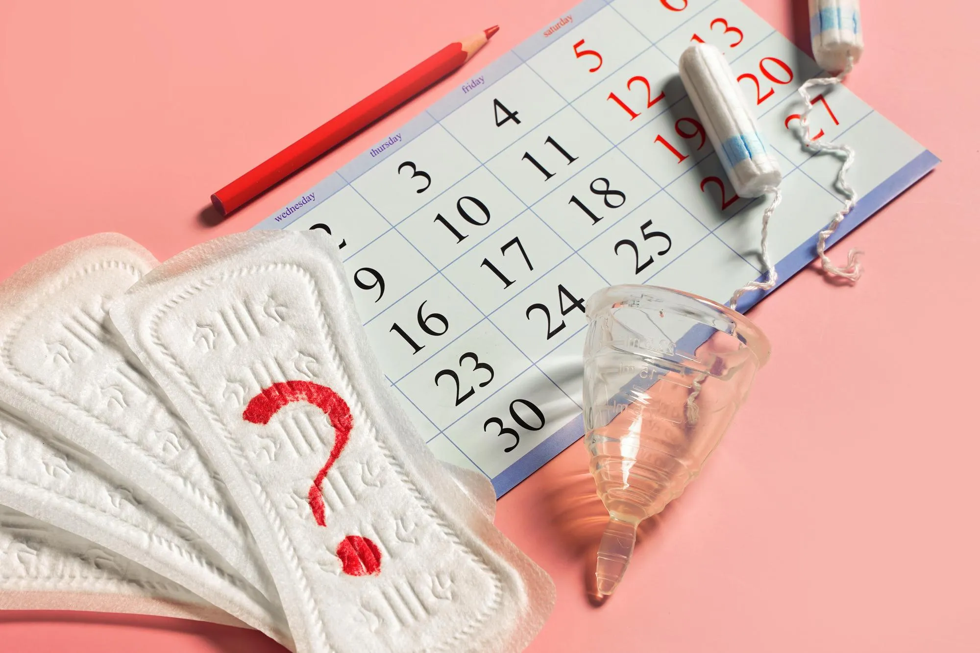 Woman menstrual cup tampons calendar control of the regular cycle pencil and sanitary pad napkin with a question close up High quality photo