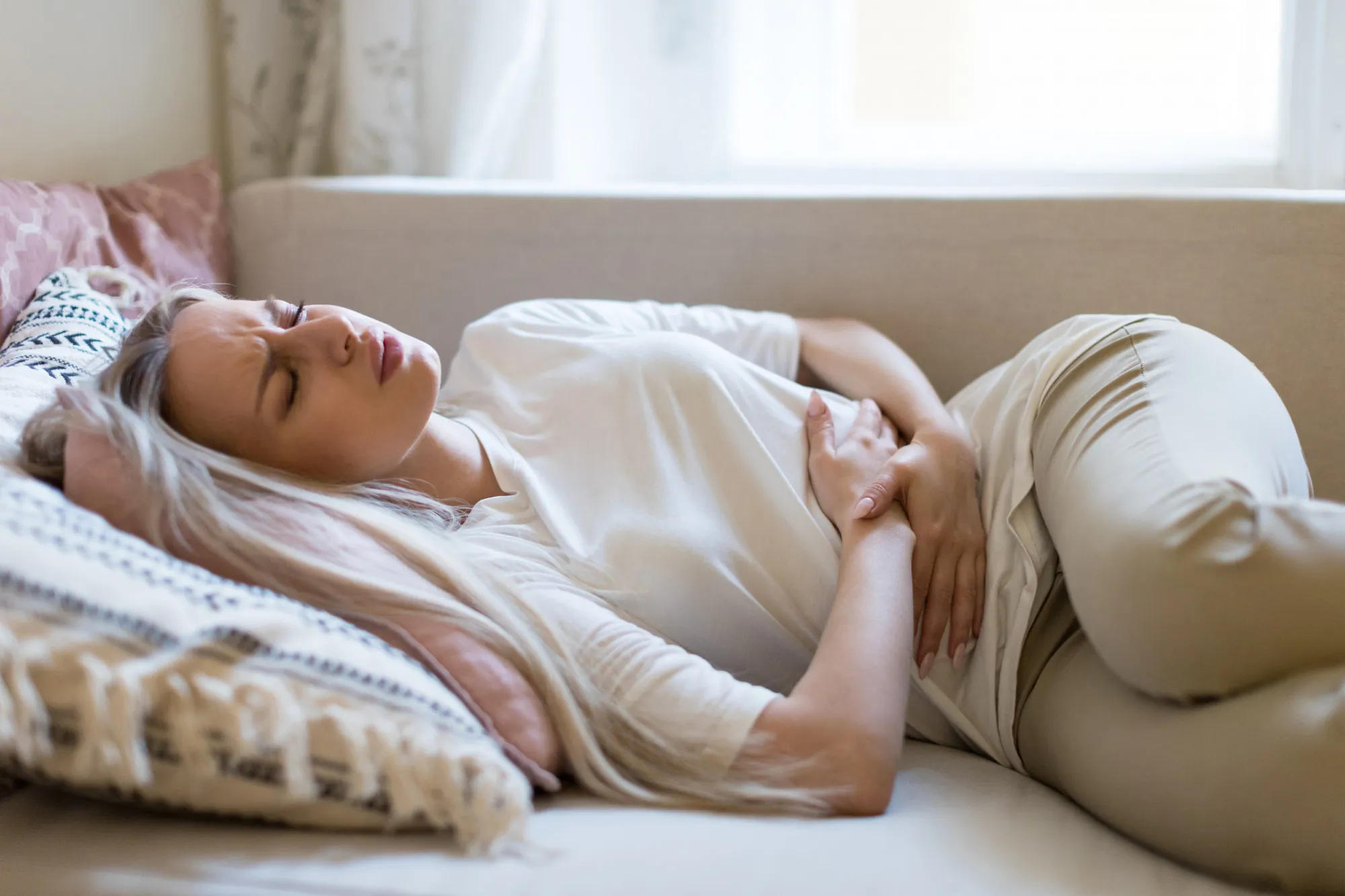 Woman suffering from stomach pain, feeling abdominal pain or cramps, lying on sofa.Period menstruation