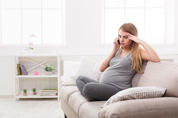 Worried pregnant woman talking on phone. Sad expectant blonde having serious conversation with her doctor. Healthcare, consultation, pregnancy problems, childbirth concept