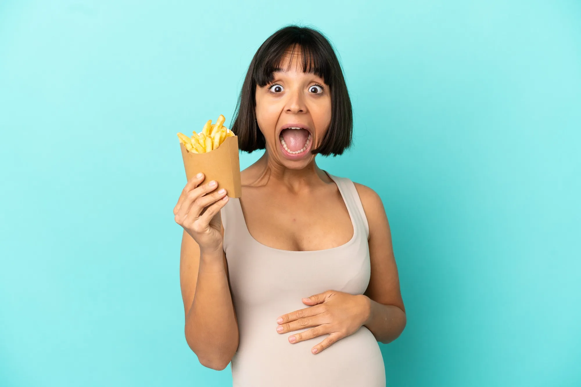 Young pregnant woman holding fried chips over isolated blue background