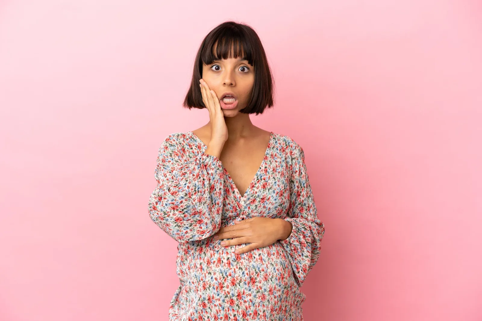 Young pregnant woman over isolated pink background with surprise and shocked facial expression