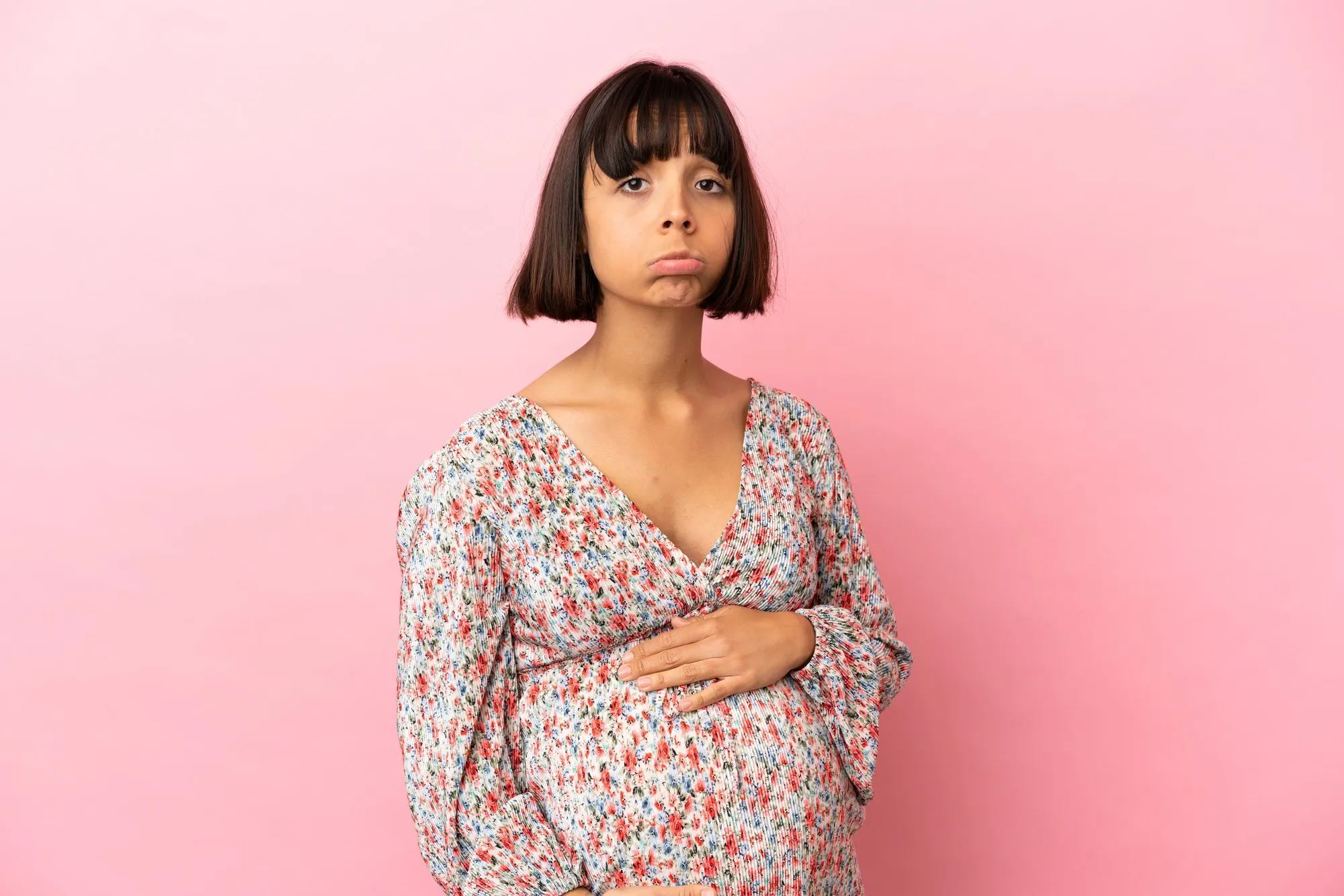 Young pregnant woman over isolated pink wall with sad expression