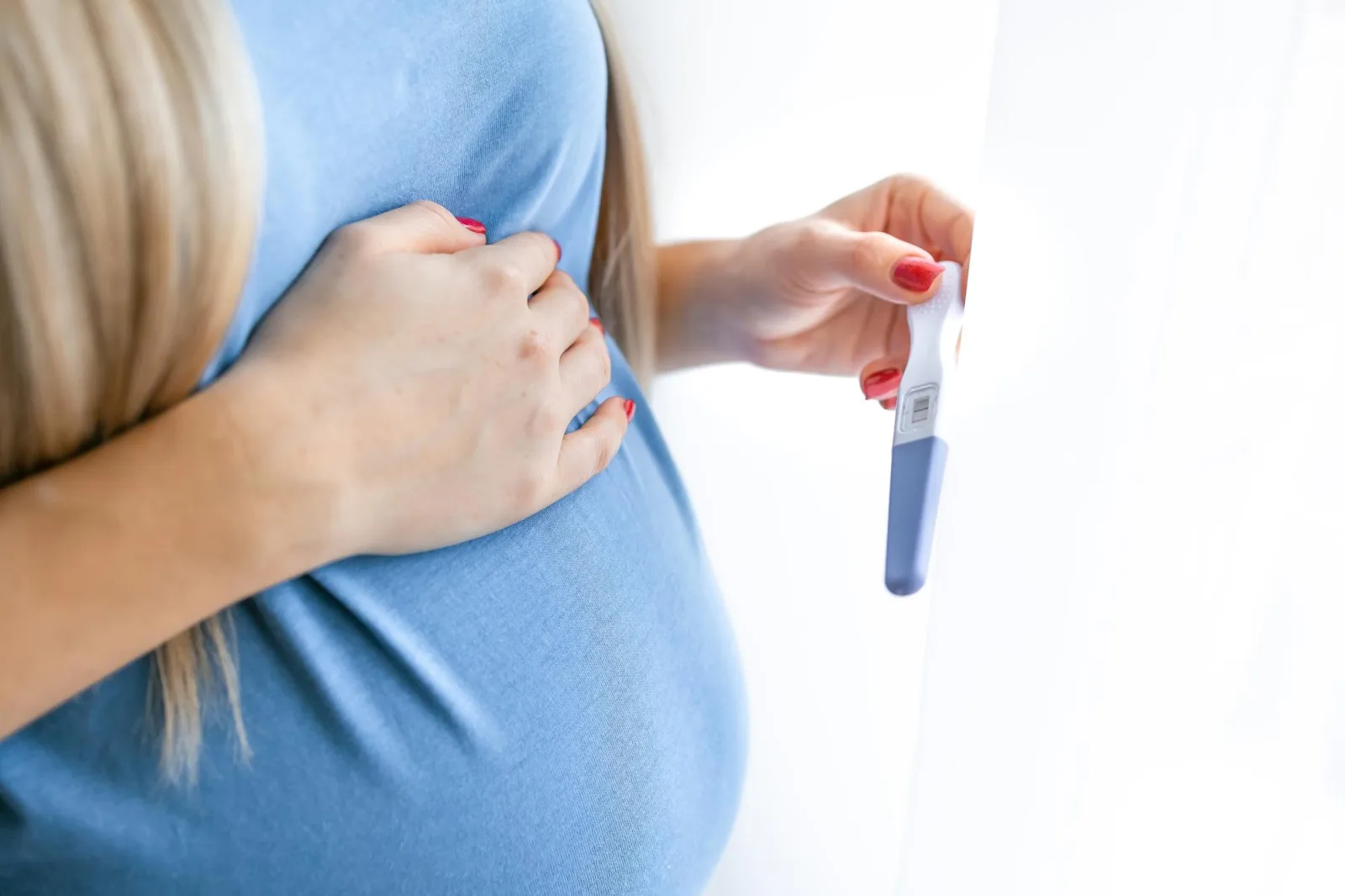 Young woman holding pregnancy test in hands and hugging her belly Concept of pregnanc gynecology medical test women health