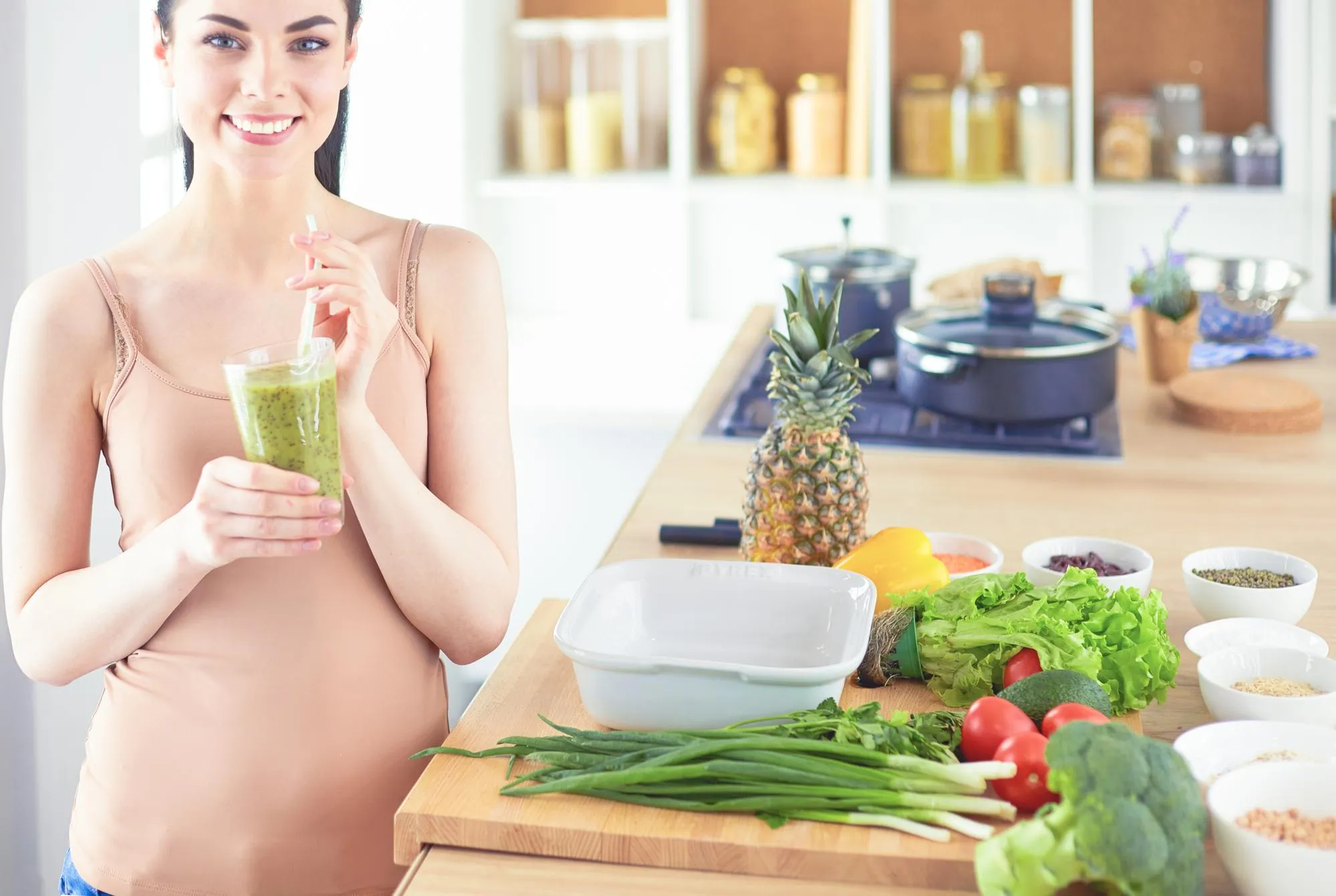 Young woman with glass of tasty healthy smoothie at table in kitchen