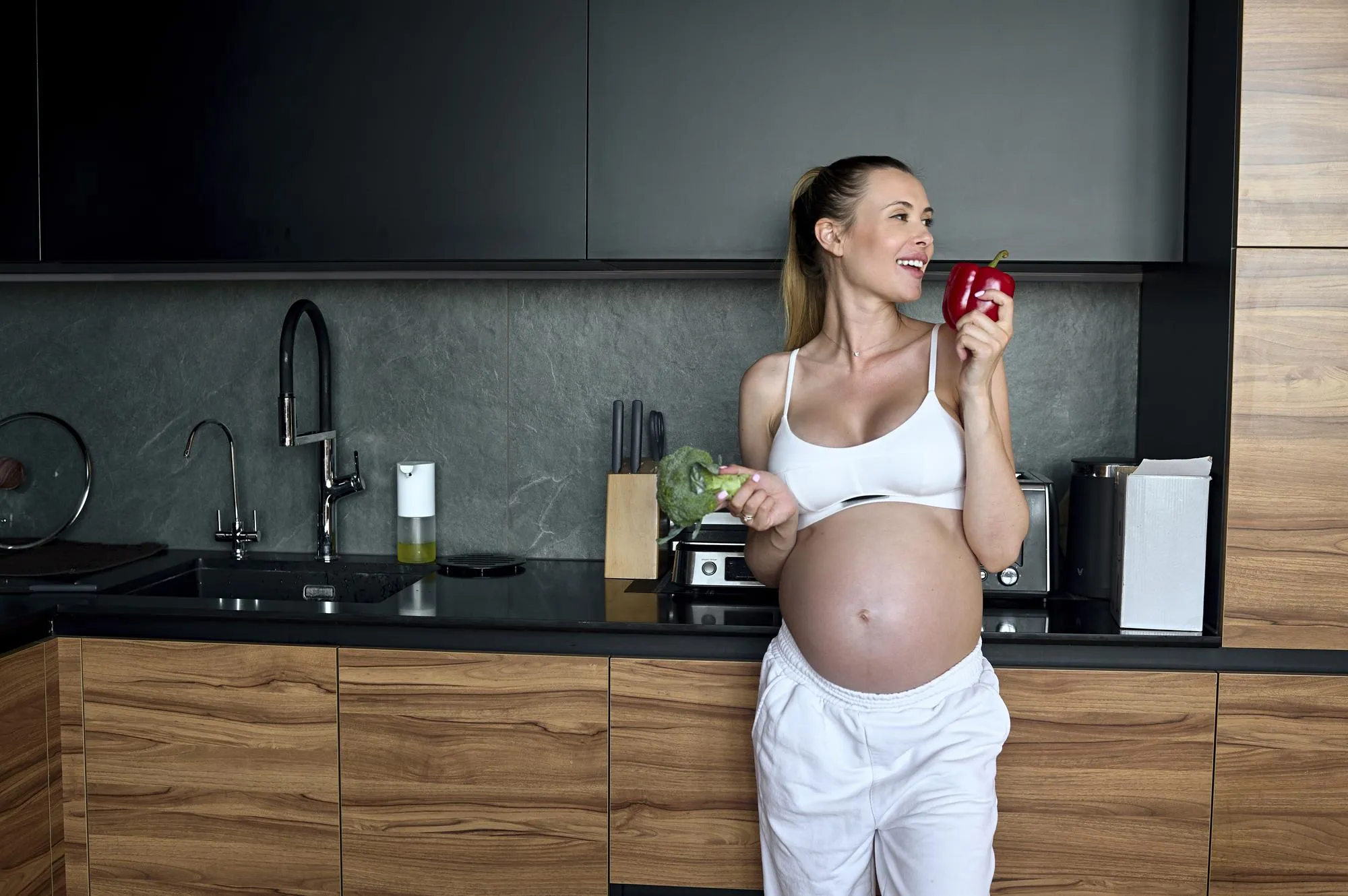 Beautiful pregnant woman making fruits smoothies with blender H