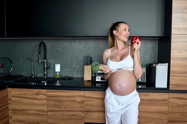 Beautiful pregnant woman making fruits smoothies with blender H