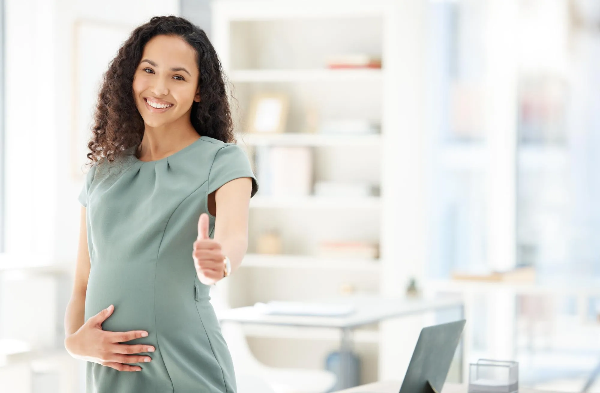 Portrait thumbs up and a pregnant business woman in her office getting ready for maternity leave from work Happy mother or support with a young female employee holding her stomach in the workplace